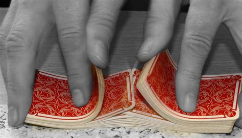 Ruky vykladača kariet nad balíčkom žolíkových kariet v šere