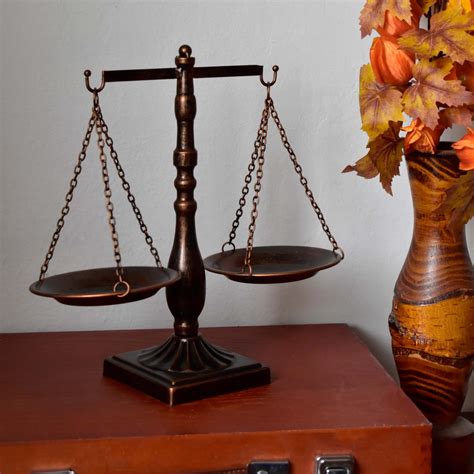 Zobrazenie bohyne Nemesis, ako drží váhy alebo kormidlo, symbolizujúce vymeriavanie spravodlivosti a rovnováhy.