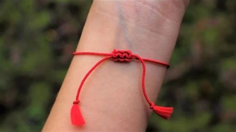 žena s červenou šnúrkou na zápästí